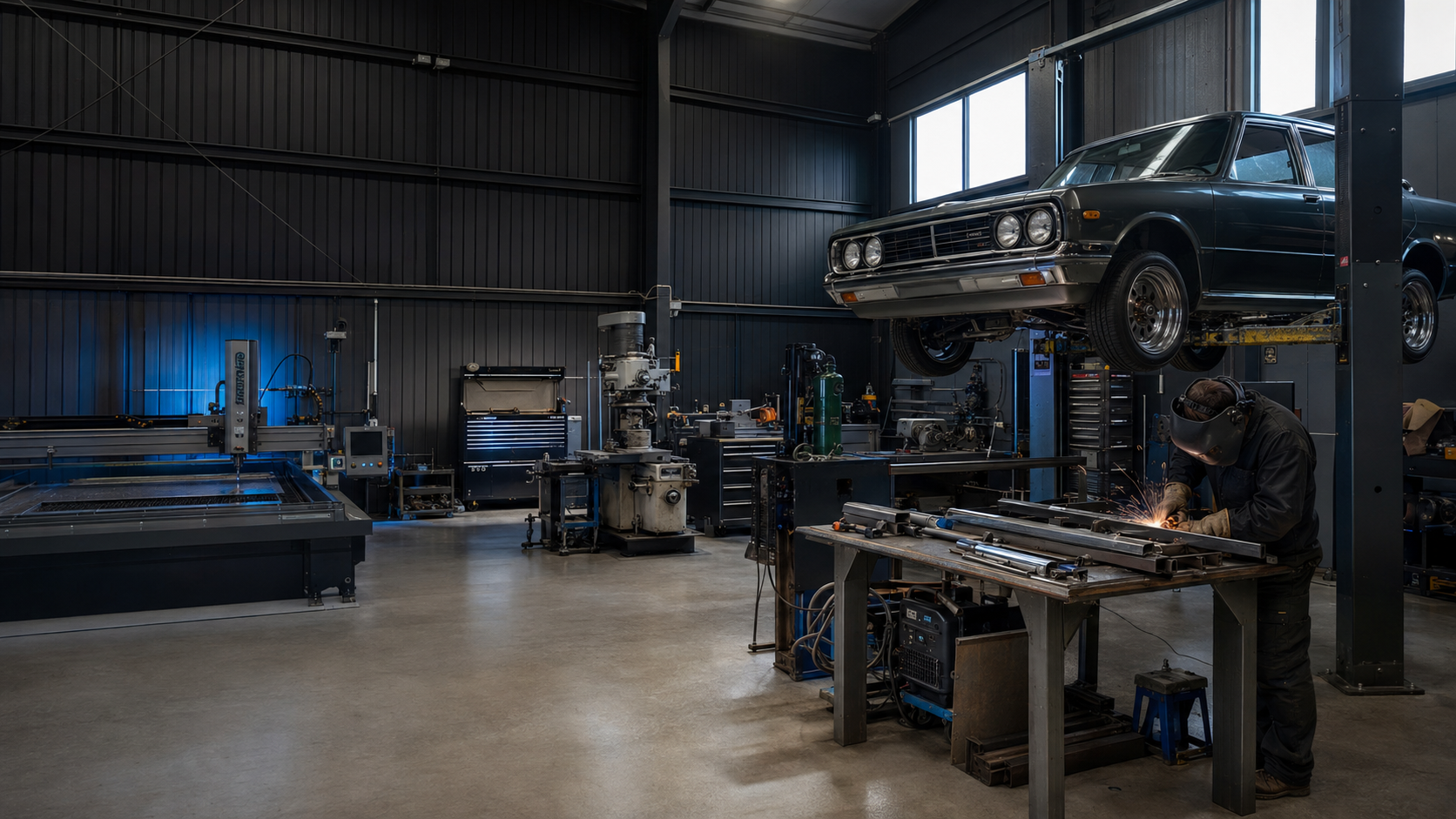 Inside the iFab Customs workshop with the CNC plasma table, lathe, milling machine and a vehicle on the hoist